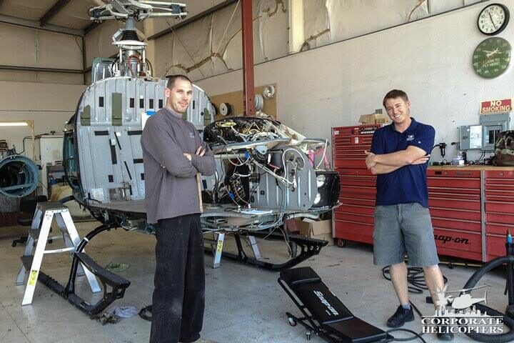Two mechanics pose for a photo during a 12 year inspection on an AS-350 helicopter