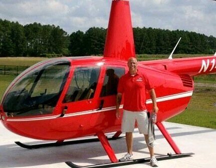 Man standing next to cherry red helicopter