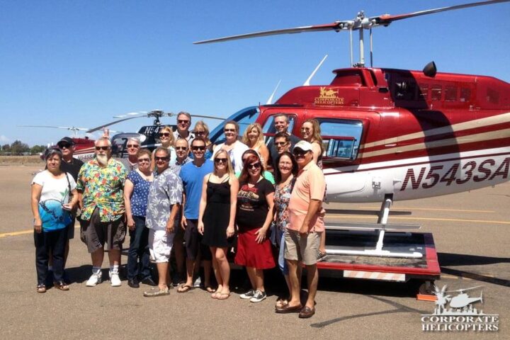A group of 21 people pose in front of a helicopter