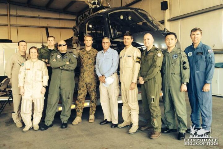 A group of National Test Pilots pose in front of a helicopter