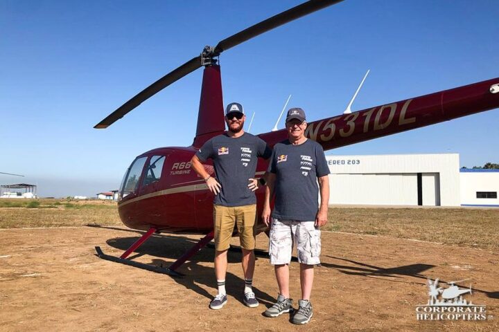 Herb Hess and Ian from Andy McMillin’s Red Bull Team in front of a red helicopter.