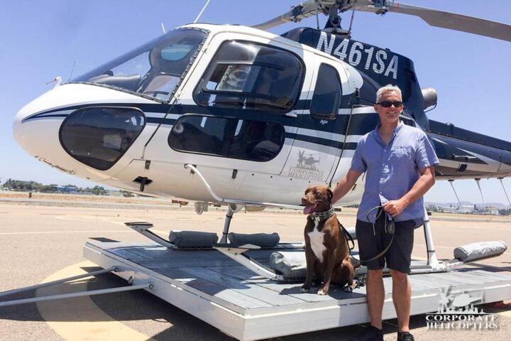 A man stands with Blade the dog in front of a helicopter