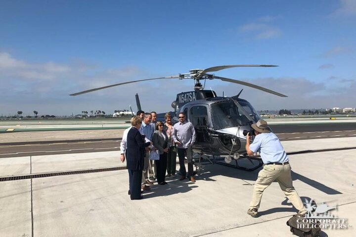 A group poses for a photographer taking their pic in front of a helicopter