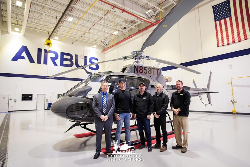 Group of men standing in front of an Airbus helicopter