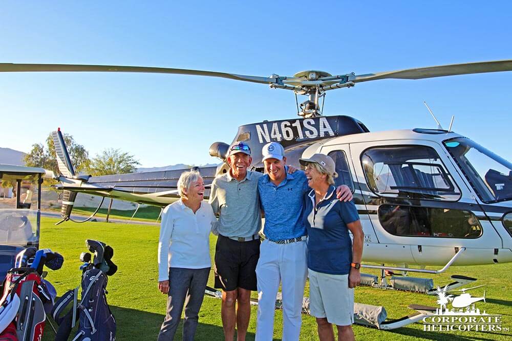 Group smiles and poses in front of helicopter on golf course