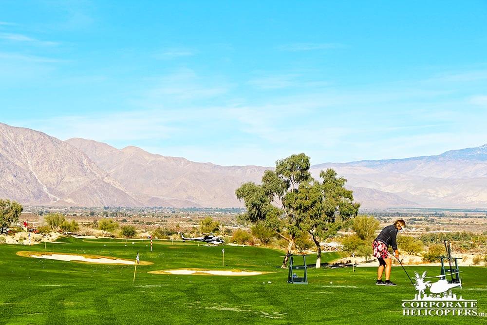 Woman about to tee off on golf course with helicopter in the background