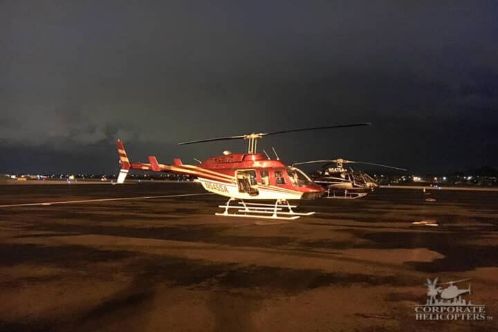 Two helicopters on an airfield at night.