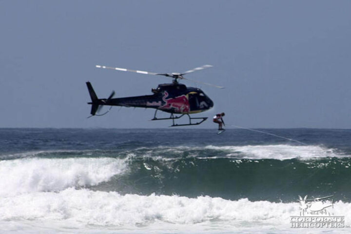 A wakeboarder dropping into ocean waves from a helicopter