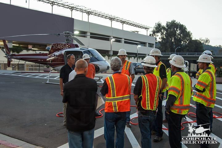A safety crew with hard hats having a meeting in front of a helicopter
