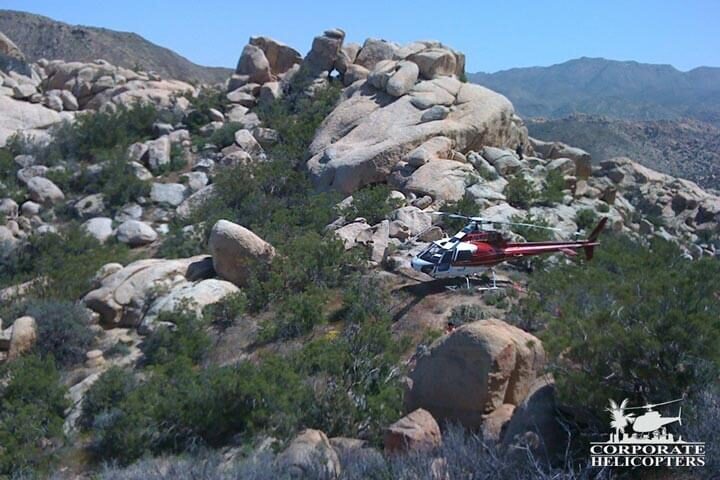 A helicopter is landed on a rocky, remote hillside