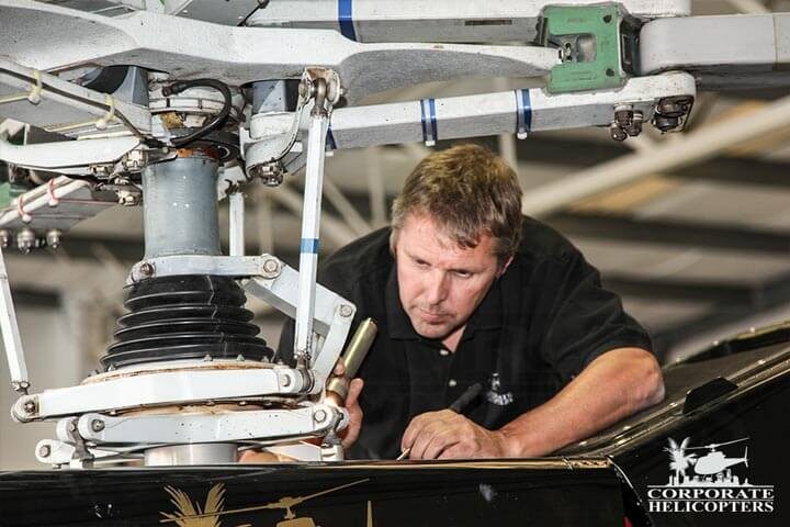 Man performing maintenance on helicopter rotor