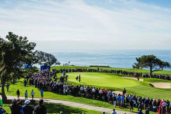 A golf course, ocean in background, and multiple spectators at the Farmer's Insurance Open