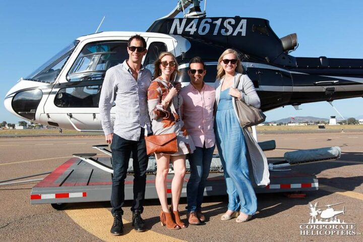 Two good looking young couples stand in front of a helicopter