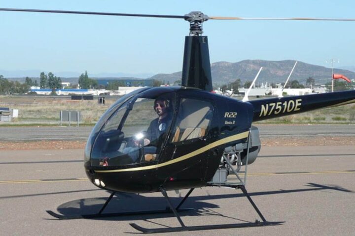 Commercial helicopter pilot sits in Robinson R22 helicopter