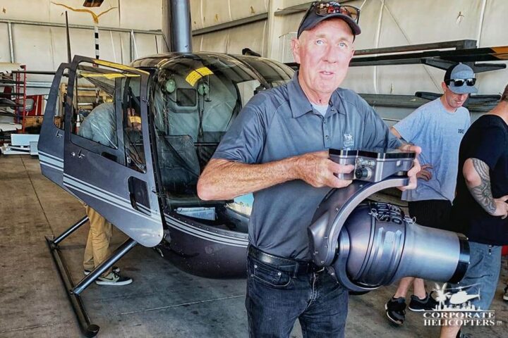 Ivor Shier holds the large Shotover B1 Camera in a helicopter hangar