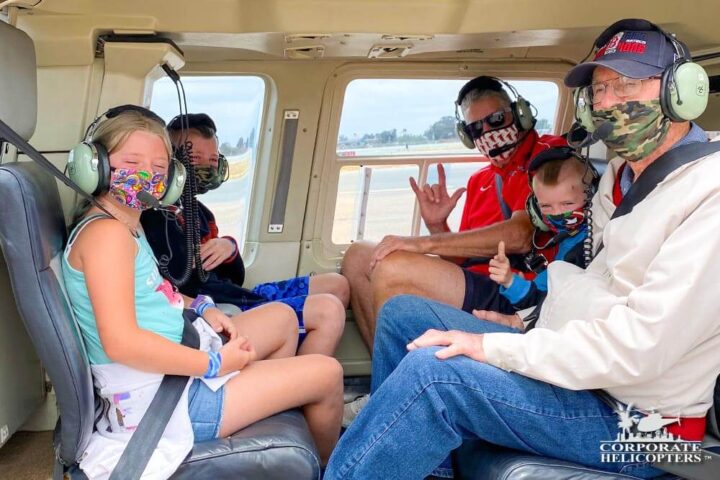 A family of 5 wearing masks in a helicopter cabin