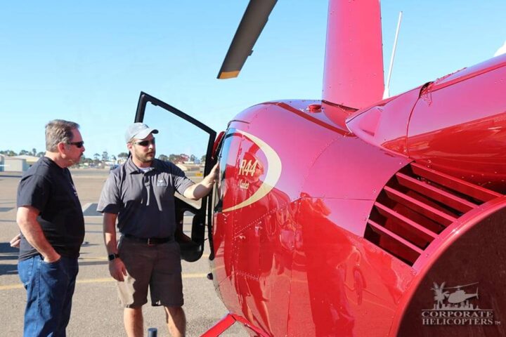 Helicopter pilot and dad next to a red helicopter