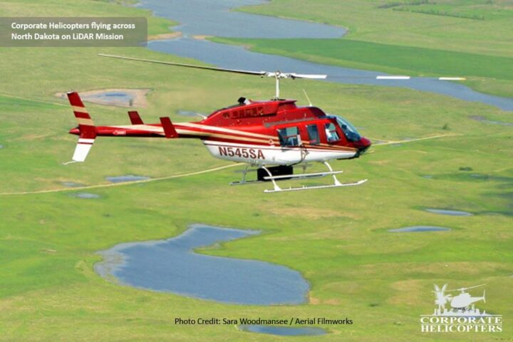 Helicopter with LiDAR qequipment flies over green land with small ponds