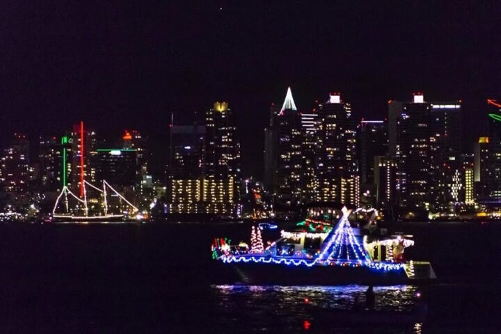 San Diego skyline with two boats lit with holiday lighting during the Parade of Lights