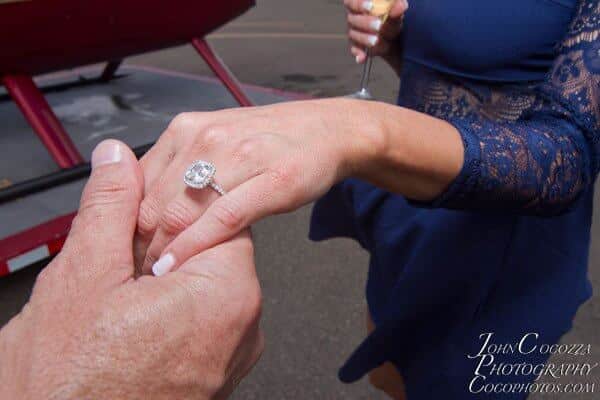 Man holds woman's hand to show off new engagement ring